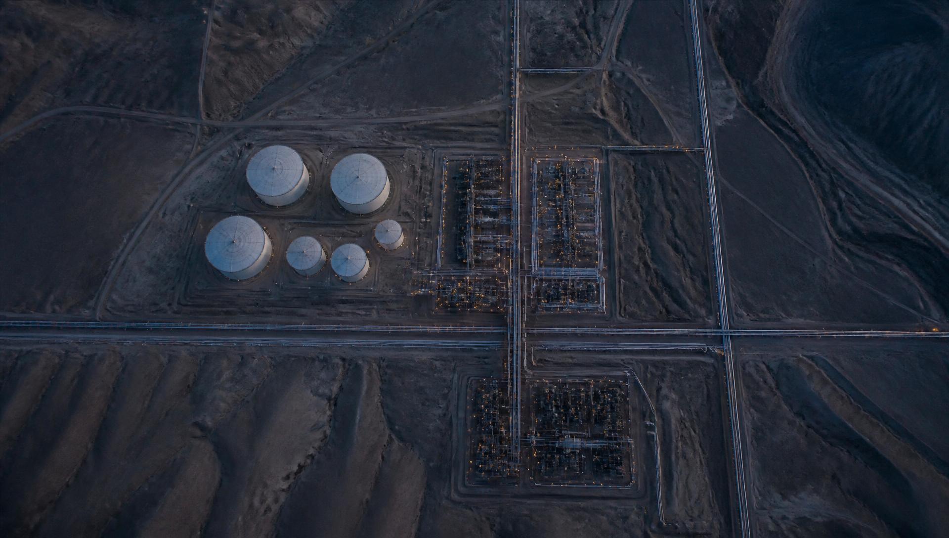 Vista aérea de una instalación energética con tanques, tuberías y corredores de transmisión